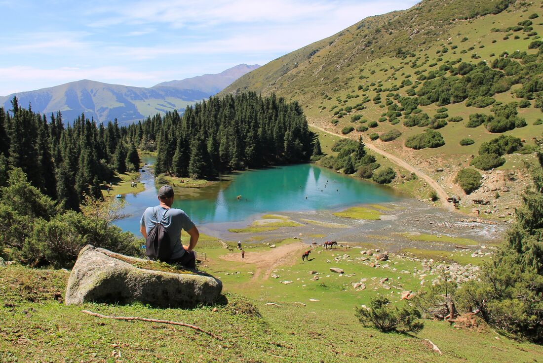 Traveller takes a break hiking in Suttu Bulak Valley in the Tien Shan Mountains of Kyrgyzstan