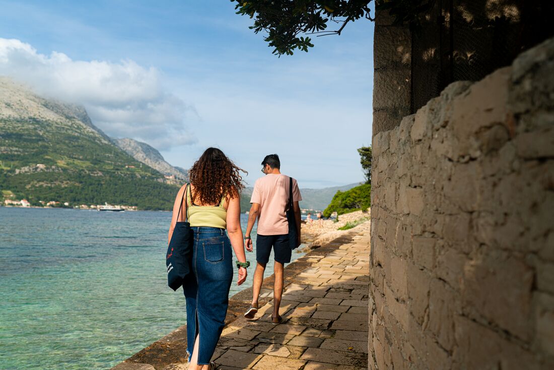 Intrepid travellers walk a stone path around the coast of Korcula island in Croatia