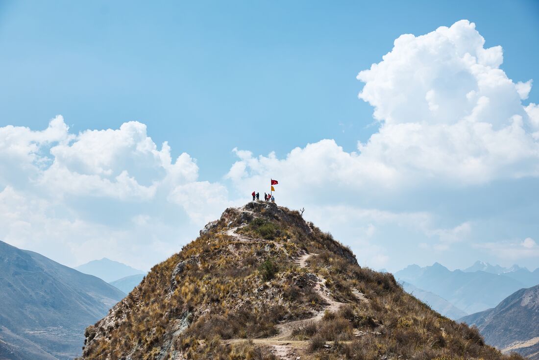 Wide distant shot of the peak of the quarry trail path with small flags and intrepid travellers gathered around