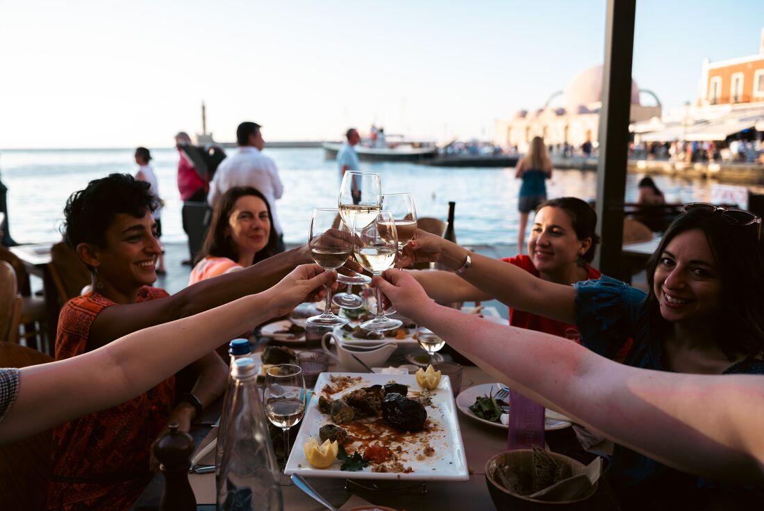 Intrepid travellers cheers in a seaside taverna in the Cyclades of Greece