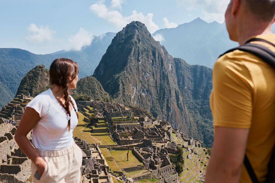 Intrepid travellers look out at the mountains and archaeological site of Machu Picchu in Peru mountains