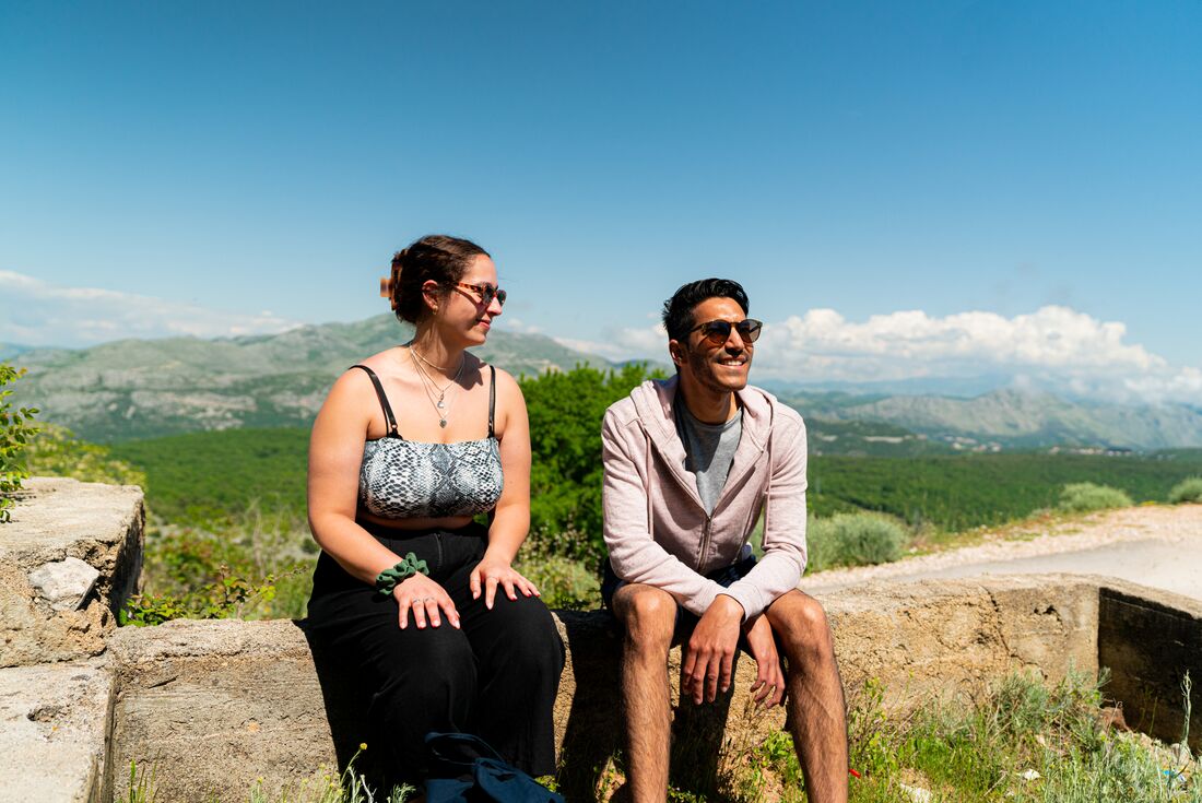 Intrepid travellers stop a hike on an ancient wall, enjoying Croatia's landscape with mountains beyond