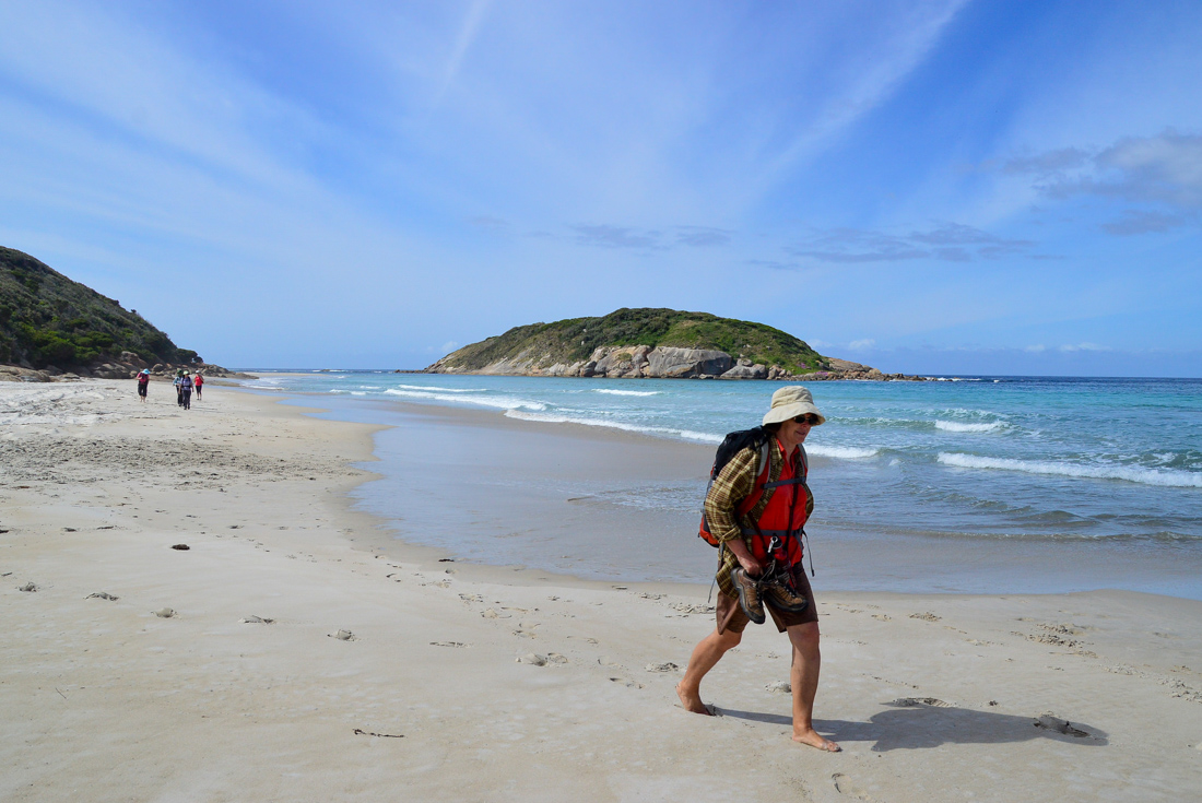 Intrepid traveller with hiking gear takes a barefoot walk along a beach on the Bibbulmun Track