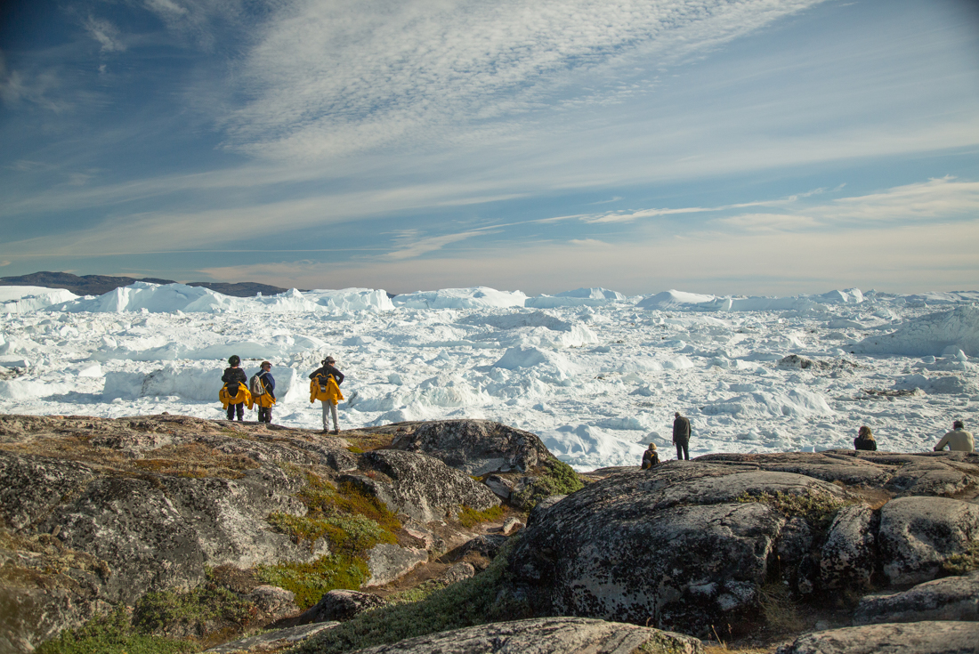Travellers looking out at glacier and ice floe landscape 