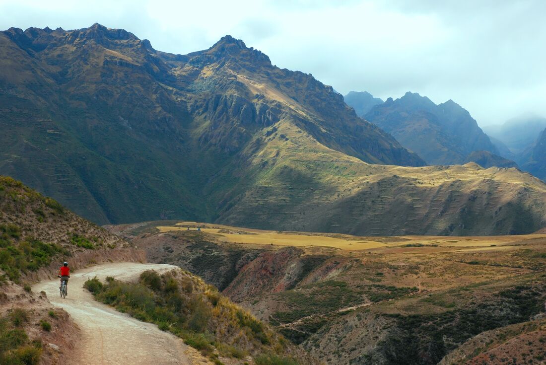 Intrepid leader on mountain bike rides ahead of group in Sacred Valley in Peru