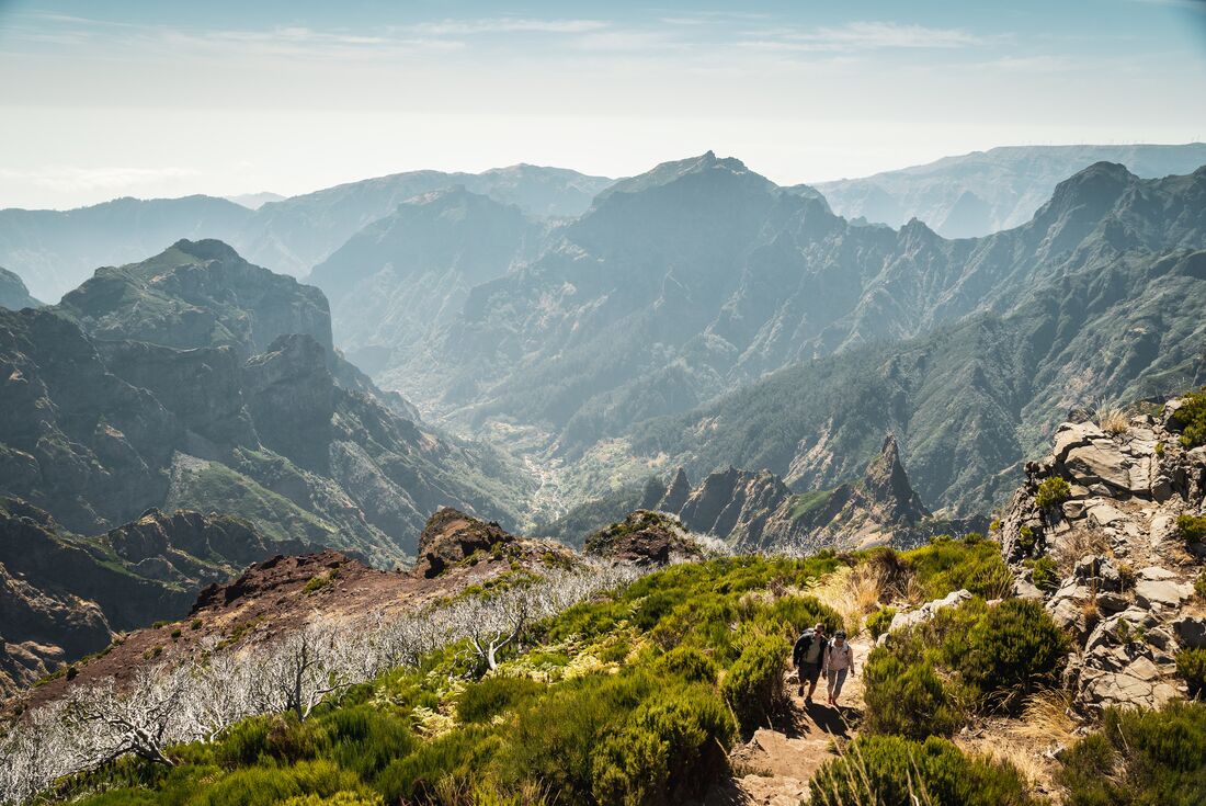 Two travellers come up the mountainside, hiking to Pico do Ruivo on Madeira island in Portugal