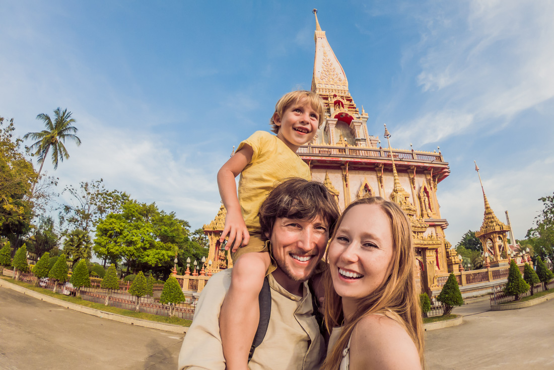 Family with parents and child pose happily for a photo in front of Wat Chalong Temple in Phuket