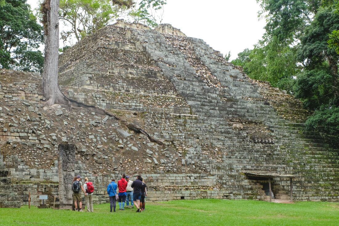 Group of Intrepid travellers on a guided tour of the Copan Ruins in Honduras at the base of a pyramid
