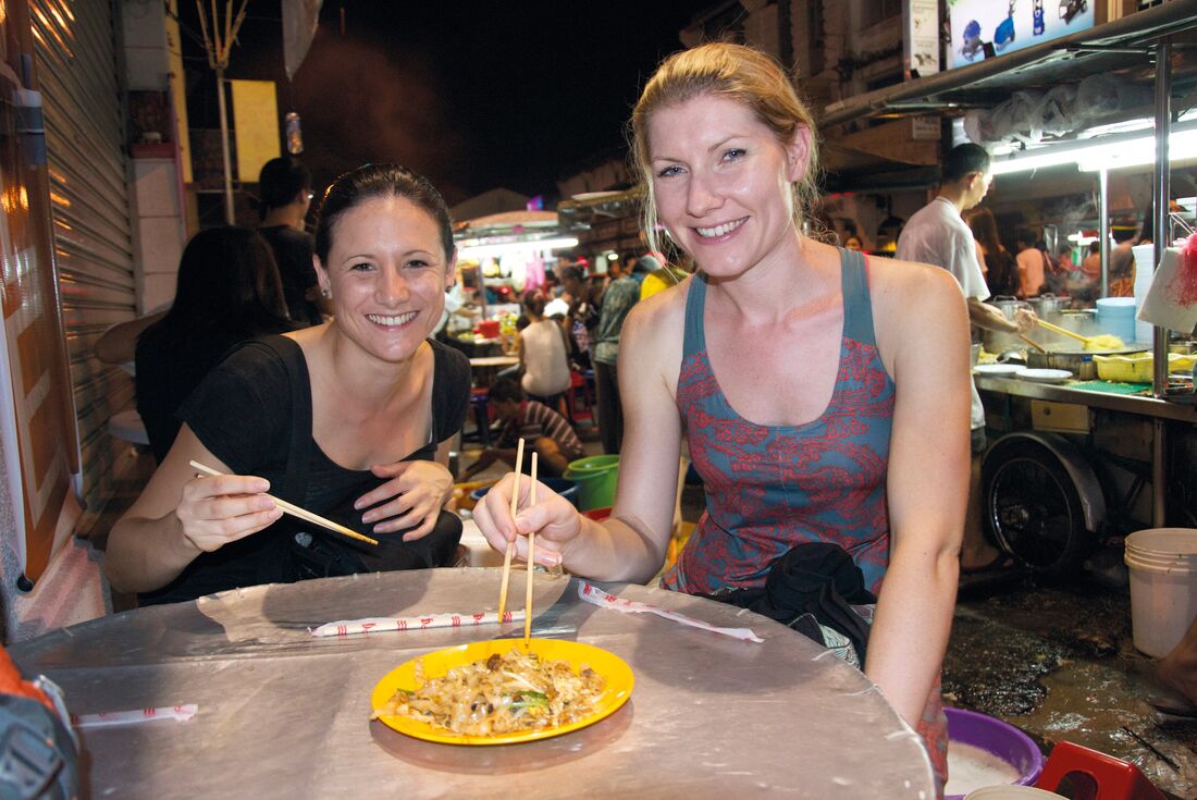 Travellers enjoying noodles from hawker street food vendor
