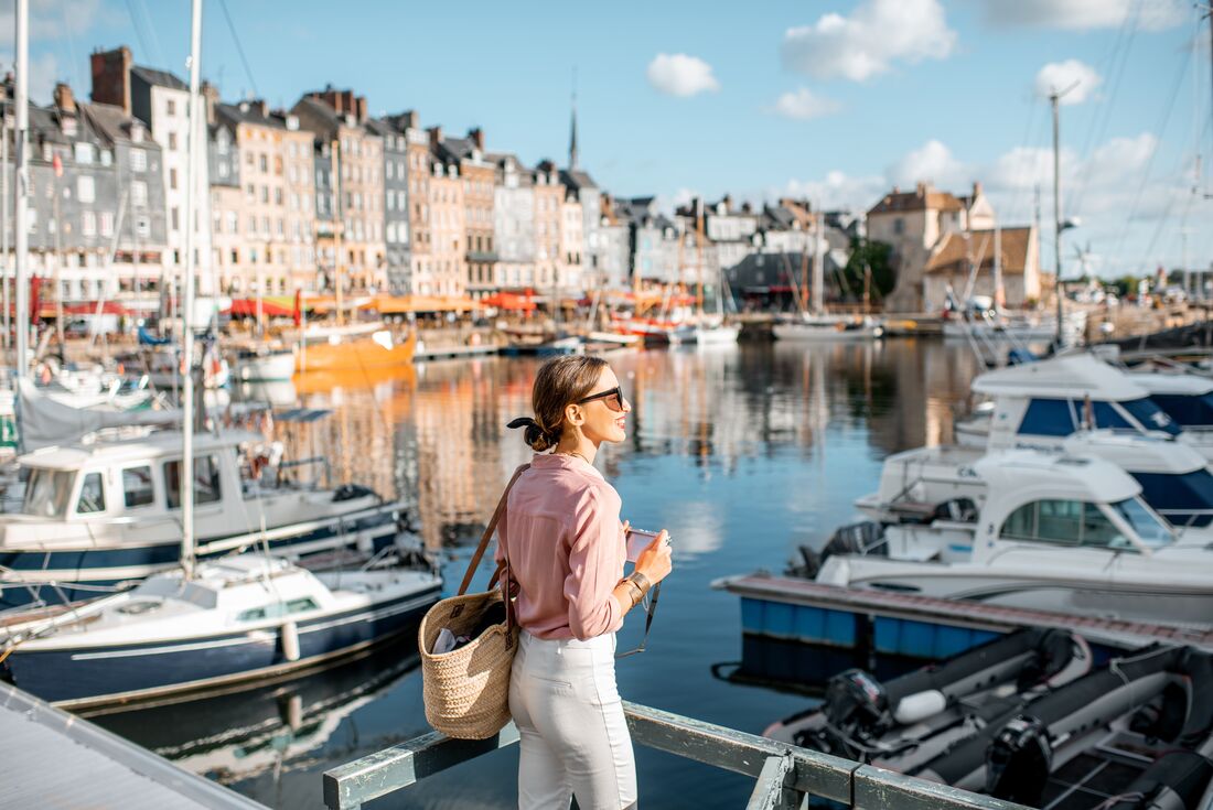 Traveller standing in front of boats and harbour at Honfleur, France