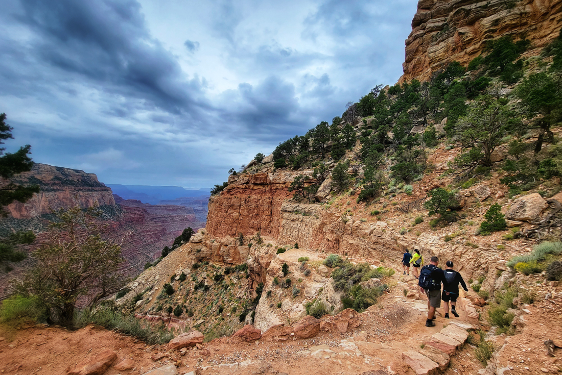 Intrepid travellers hiking along the South Rim with a grand view beyond
