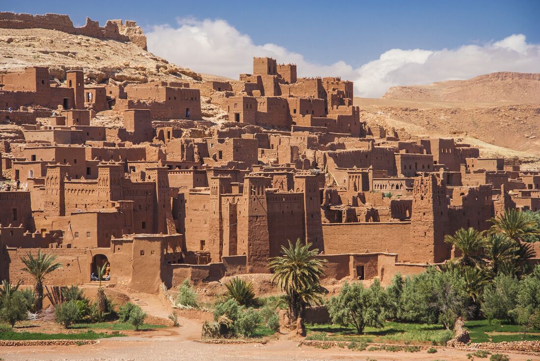 Ancient earthen city of Ait Benhaddou stacks up the hill of the desert in Morocco