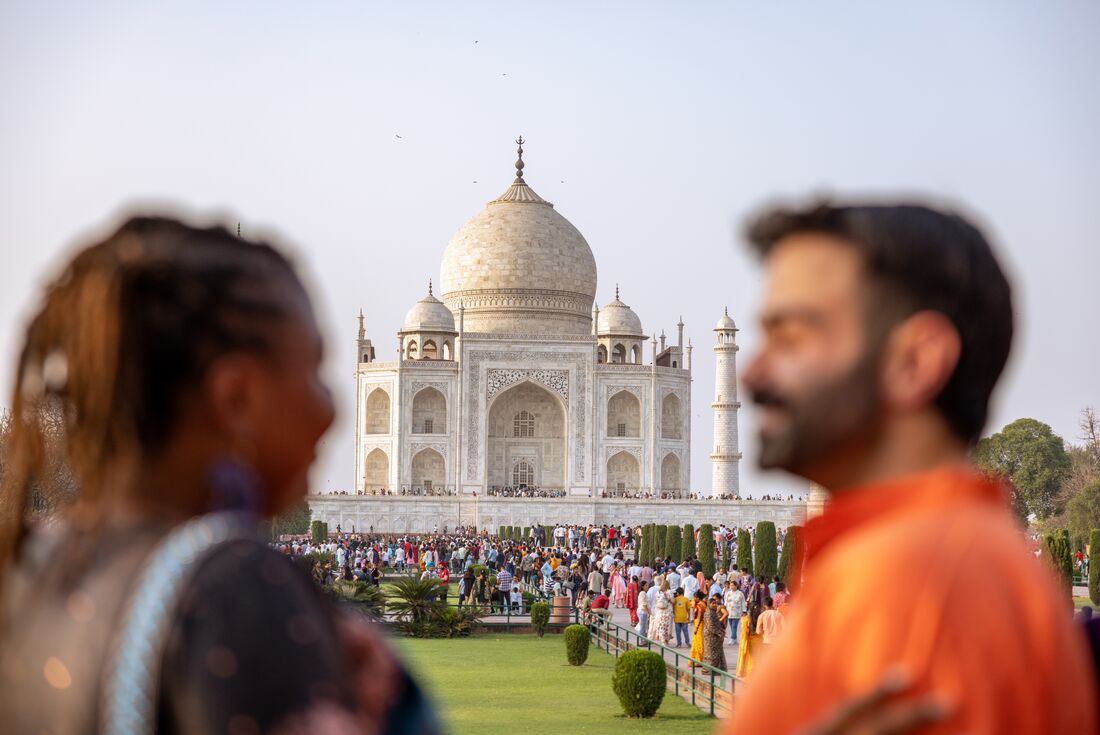 Travellers smile and laugh with each other looking out at the Taj Mahal in Agra