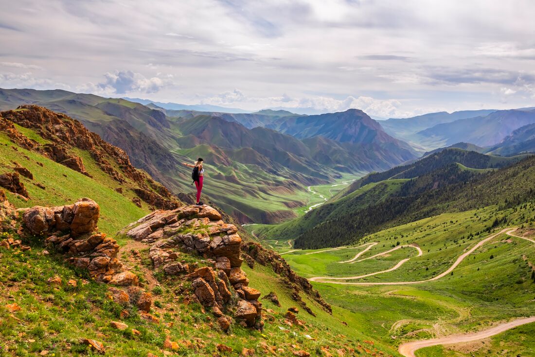 Intrepid traveller stops for a lookout while trekking in the Tien Shan Mountains of Kyrgyzstan