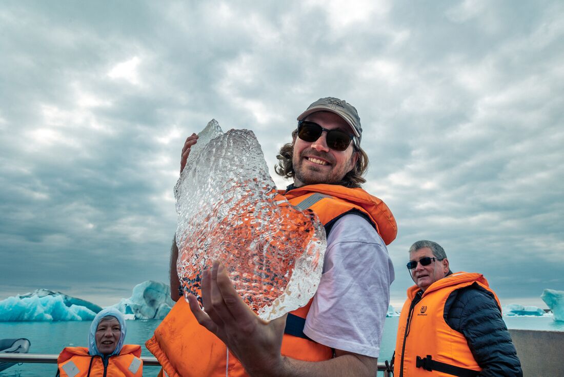 Traveller holding massive ice shard on Jokulsarlon Glacier Lagoon boat tour