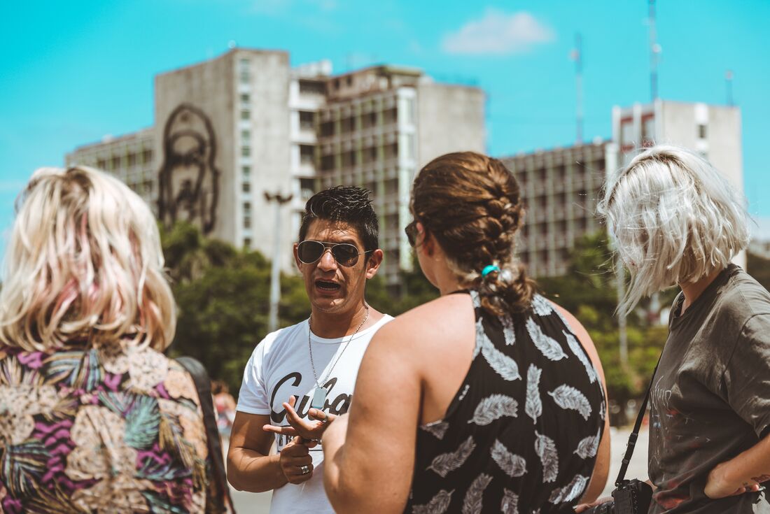 Travellers learn from a local guide about the Cuban Revolution in Havana Cuba