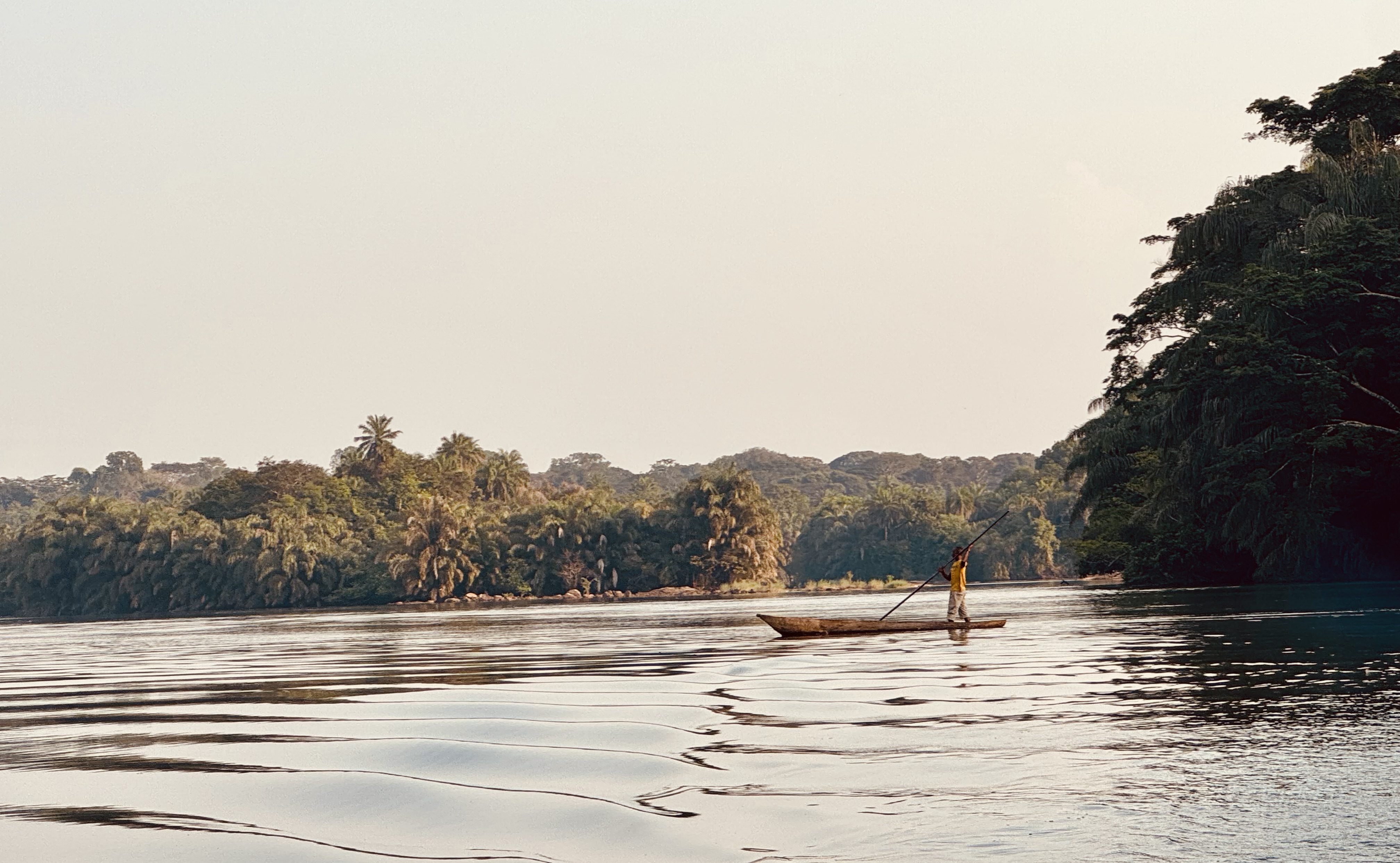 A person stands rowing on a boat along the Moa River in Sierra Leone