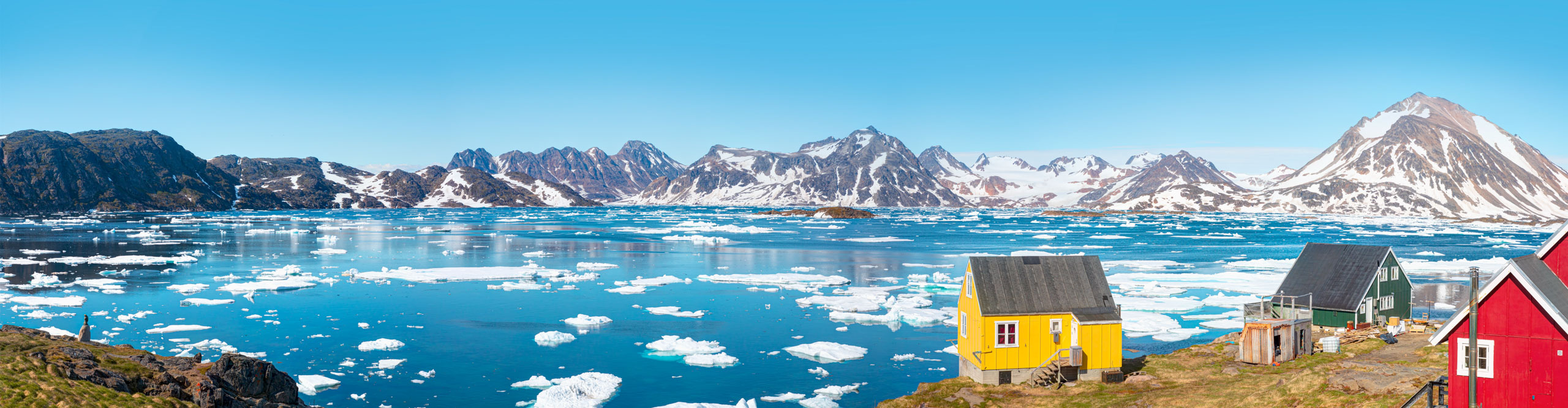 View of Kulusuk village in Greenland on a clear sunny day with colourful houses in view