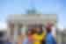 Four 18 to 35s travellers in colourful outfits take a selfie in Berlin near the Brandenburg Gate