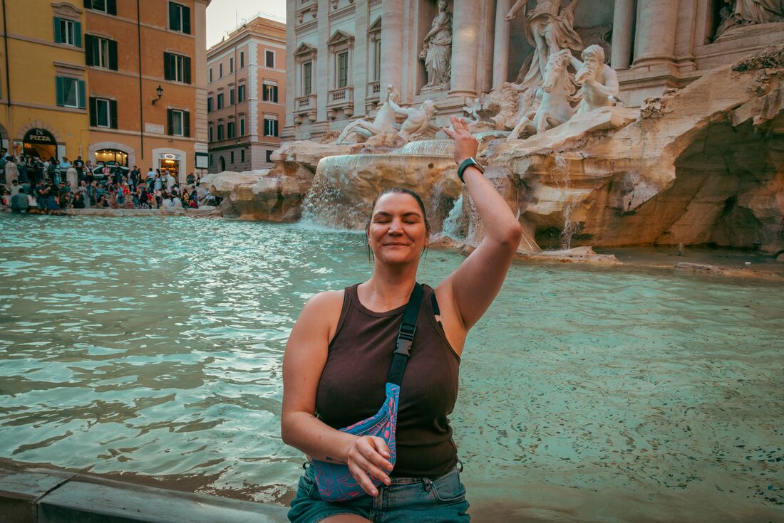 Traveller Rachael Sarra throwing a coin into Trevi fountain in Rome in the evening