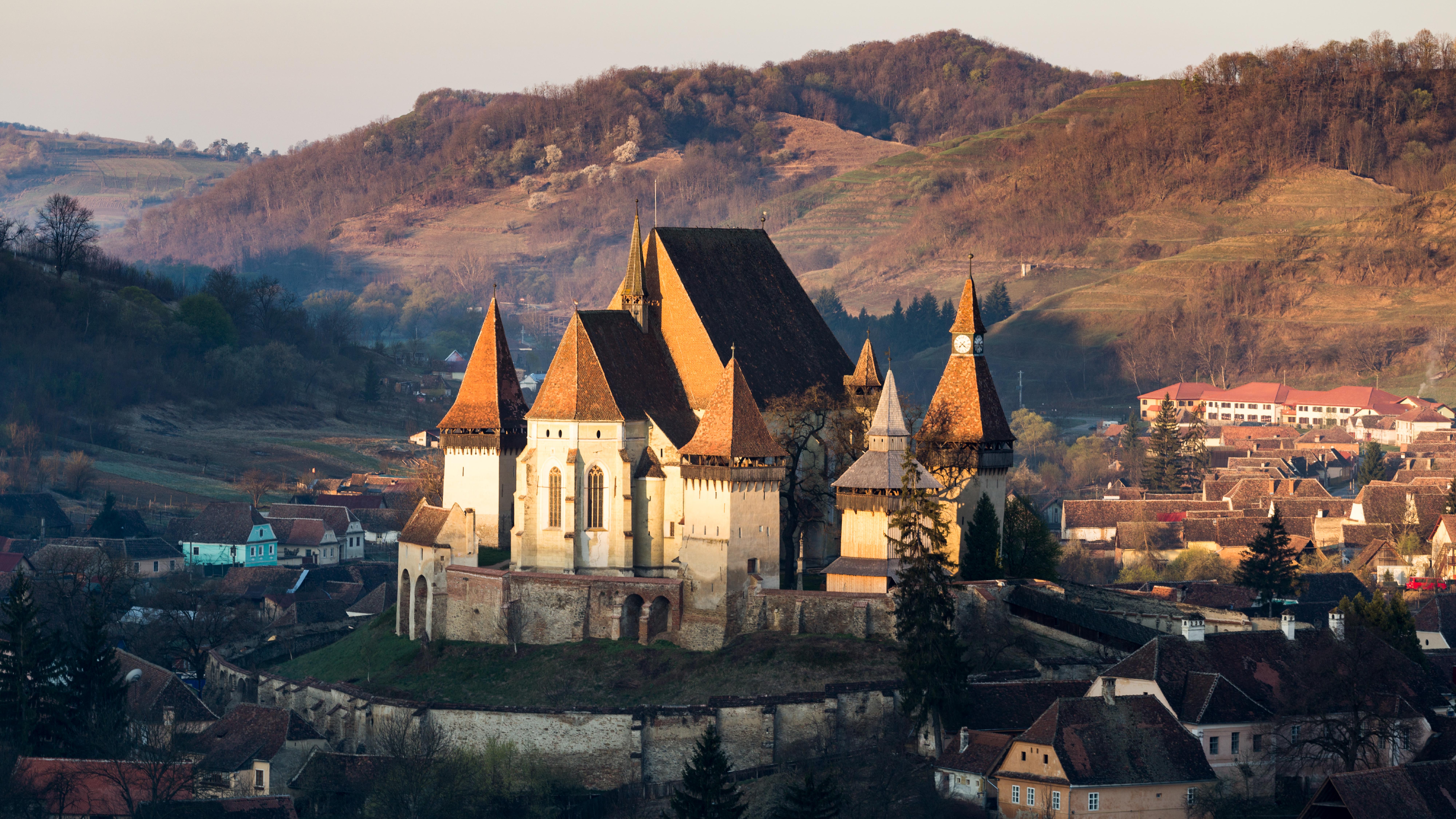 A photo of the sun rising on a castle Terra Saxonum, a stop along Romania's Via Transilvanica.