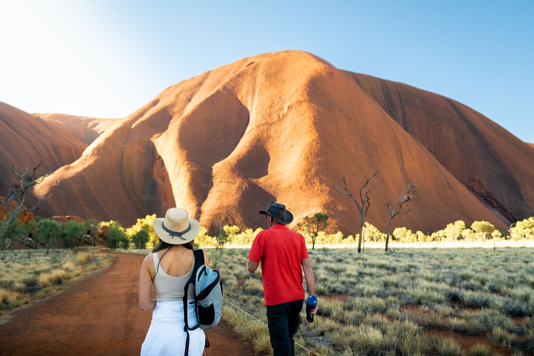 Intrepid travellers and leader approach the foot of Uluru for a talk