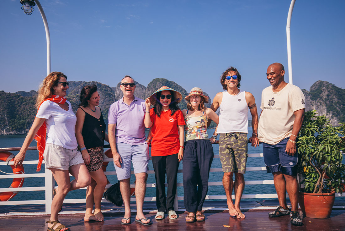 Passengers on board boat in Halong bay pose for camera with mountains behind them