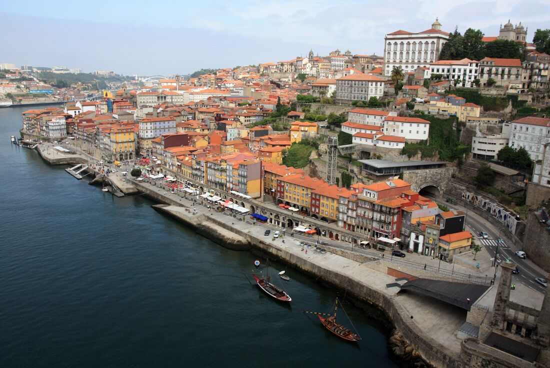 Aerial shot of riverside Porto in Portugal, showing boats docked and colourful building facades 