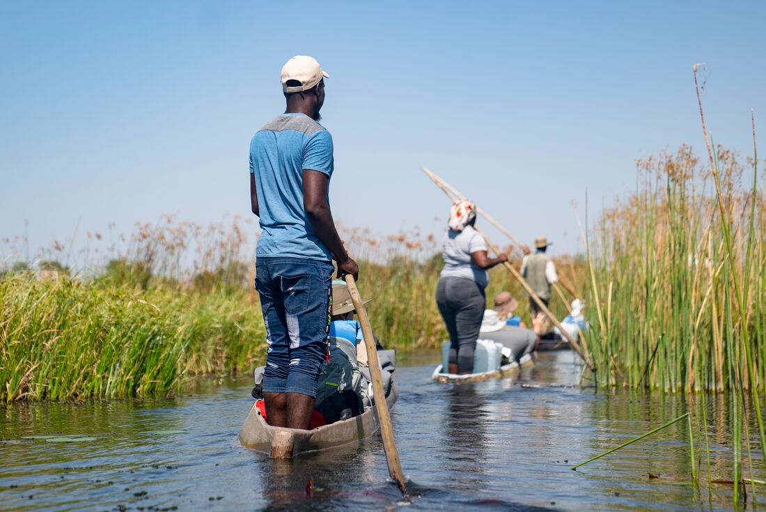 Local guides taking travellers on a canoe ride on Okavango Delta, Botswana