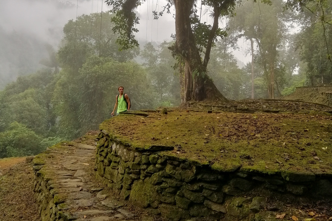 Traveller looks around a Ciudad Perdida terrace on a misty morning in the Sierra Nevada mountains in Colombia