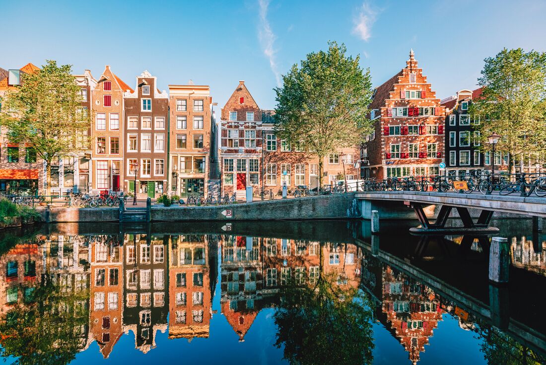 Amsterdam canal streets in the afternoon sunlight with bicycles parked everywhere and locals crossing bridges