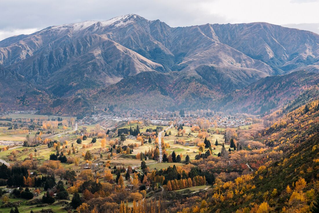 Aerial view of Arrowtown, warm autumn colours and mountainscape in the background