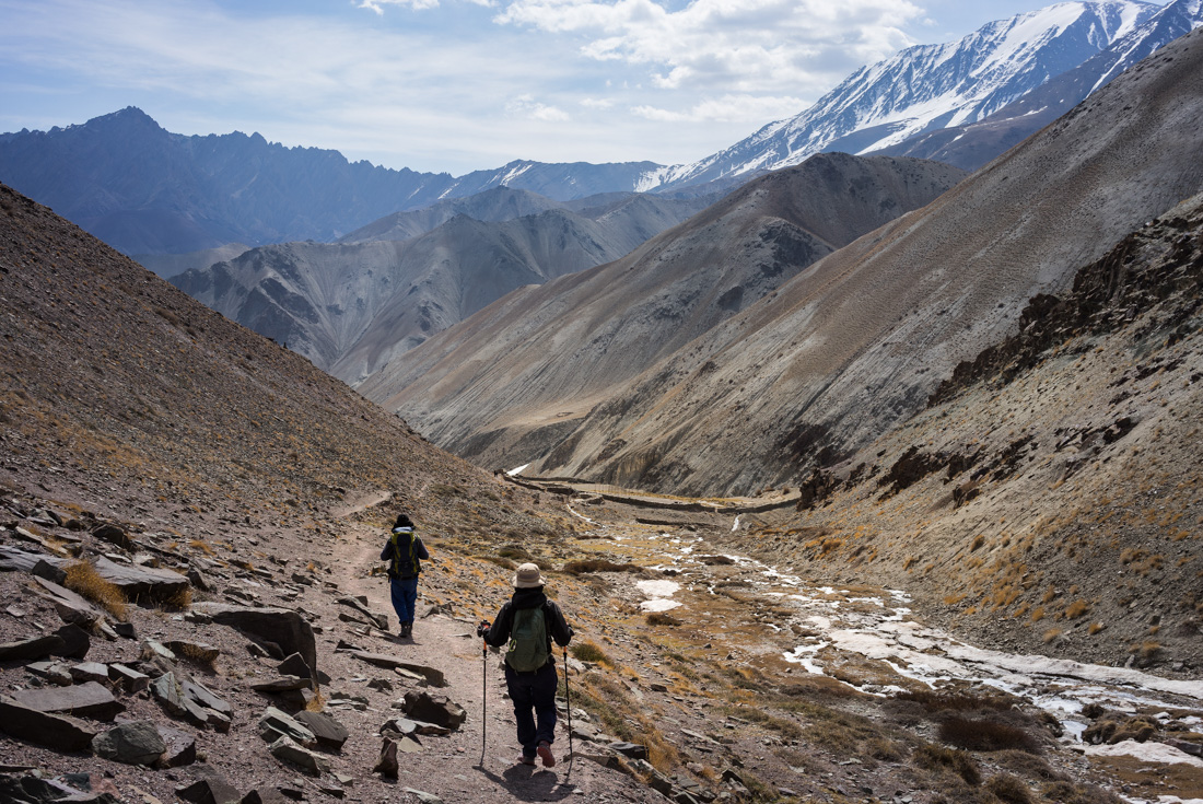 Travellers with hiking sticks hiking in a mountain pass on the Markha Valley trek in Ladakh