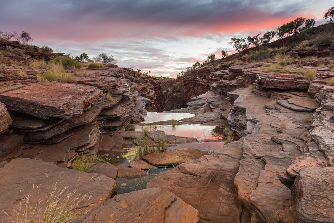 Pools of water reflect the sky at sunset on Karijini gorge in Western Australia