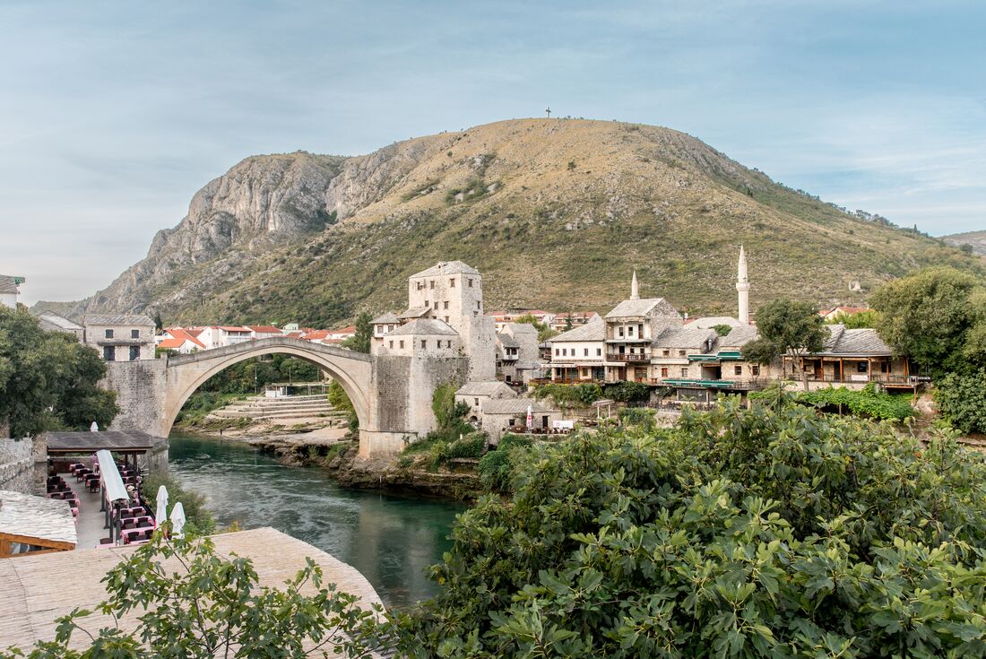 Wide shot of Mostar village with famous bridge in Bosnia and Herzegovina and mountains beyond