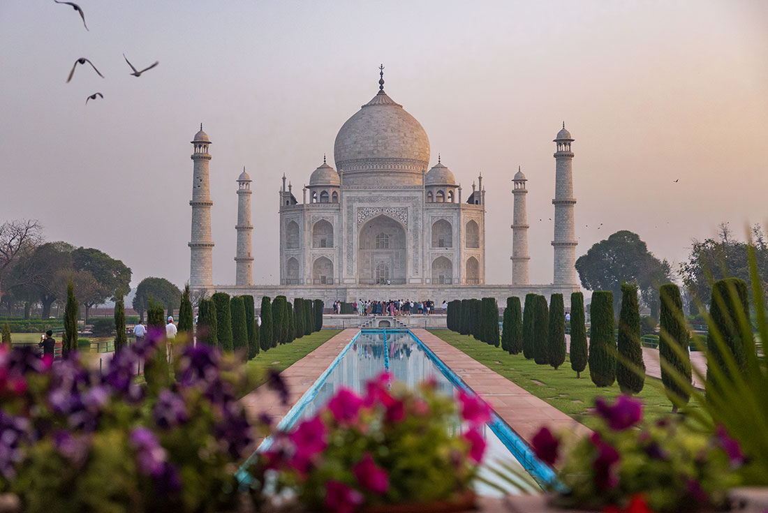 The pointed domes of the Taj Mahal and its towers lit by the slow glow of the sunrise near Agra in India