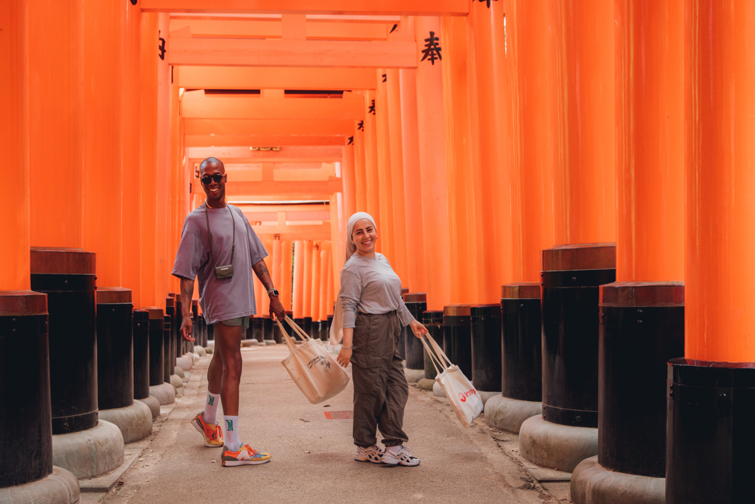 Intrepid travellers having fun while exploring Fushimi Inari shrine walking through the orange gates near Kyoto