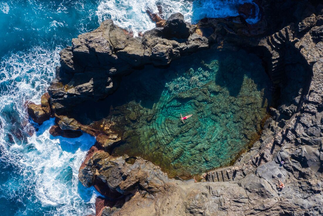 Traveller floats in natural coastal pools of El Calenton on Tenerife in the Canary Islands of Spain