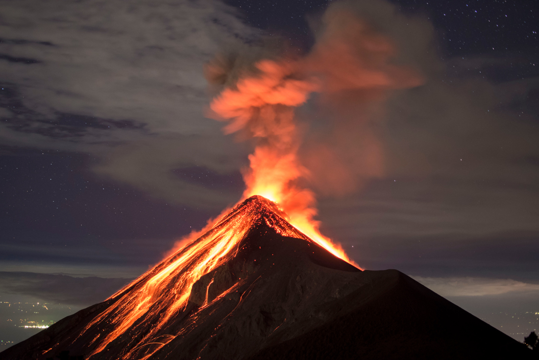 Volcano Fuego eruption seen from the slopes of Fuego, with Antigua's lights behind