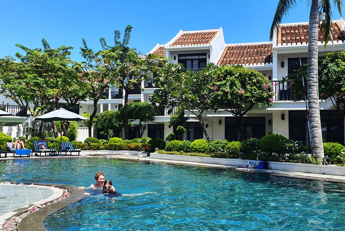 Children in swimming pool as family relax by the pool at the Hoi An resort accomodation, Vietnam