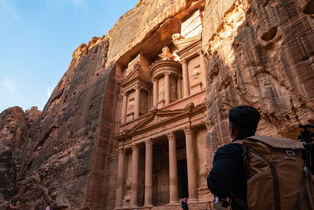 Intrepid traveller looks up the detailed carved stone facade of Al-Khazneh in Petra, Jordan