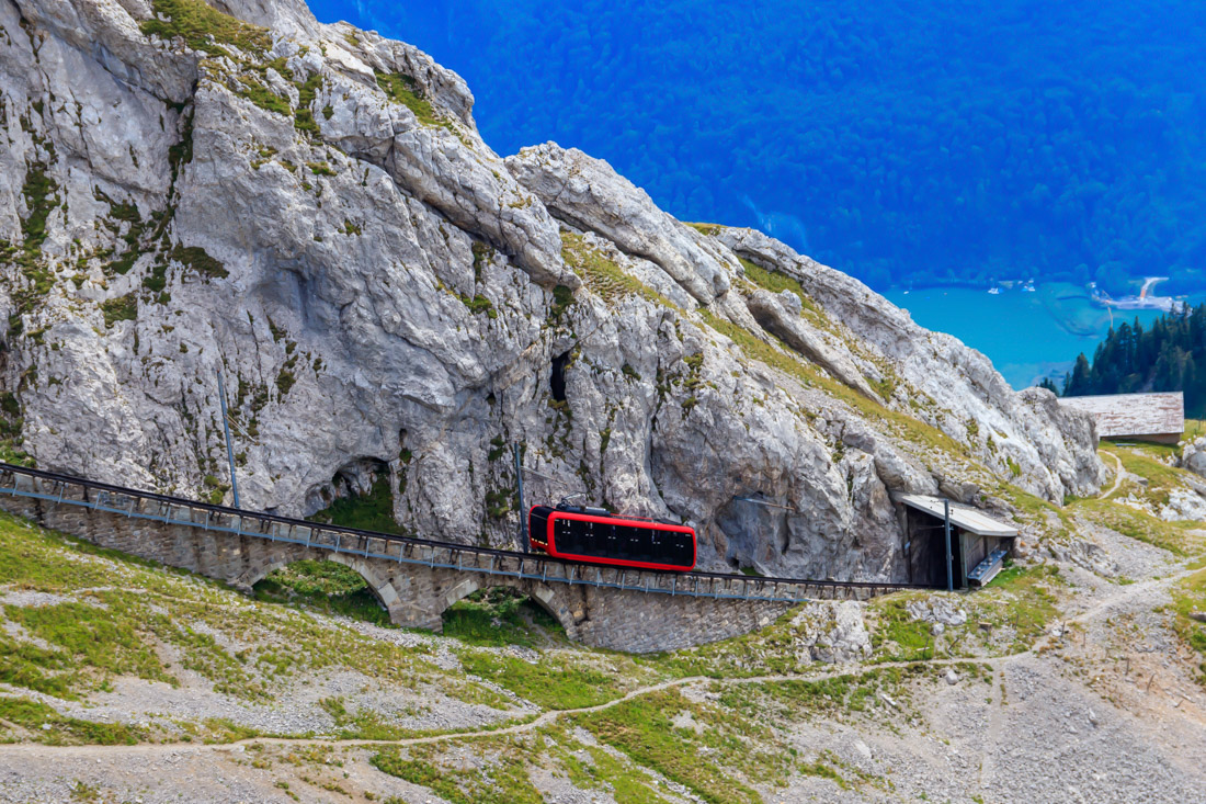 A cogwheel train ascending Mount Pilatus in Lucerne Switzerland, with a distant lake visible below in the background